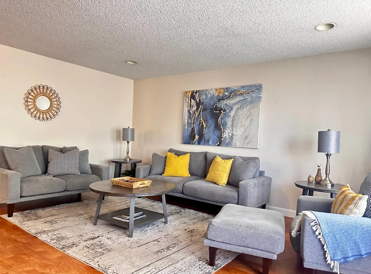 This image depicts a comfortable living space with plush sofas, a coffee table, stylish accent pillows, and mirrored wall decor. The room invites socializing, relaxing, and sharing stories—activities that resonate with family togetherness after a day of local exploration.